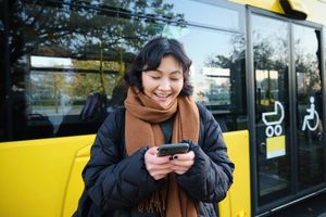 Beautiful korean girl student bus stop looking her smartphone checking timetable reading text