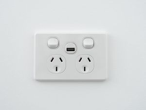 Socket with USB interface and switch on a white wall.