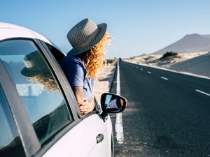 Woman looking out of a car on the side of the road.